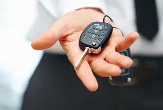 Clé de voiture remise : transaction automobile ou location Gros plan sur une main tendue présentant une clé de voiture moderne avec télécommande intégrée, probablement remise par un vendeur ou un voiturier.